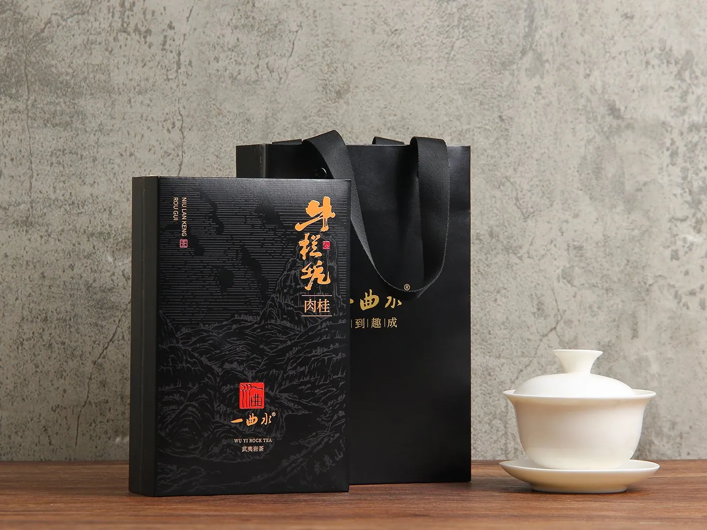 牛栏坑肉桂 · 礼盒正面（玄色墨玉匣 + 岩褐手提袋 + 白瓷盖碗）
